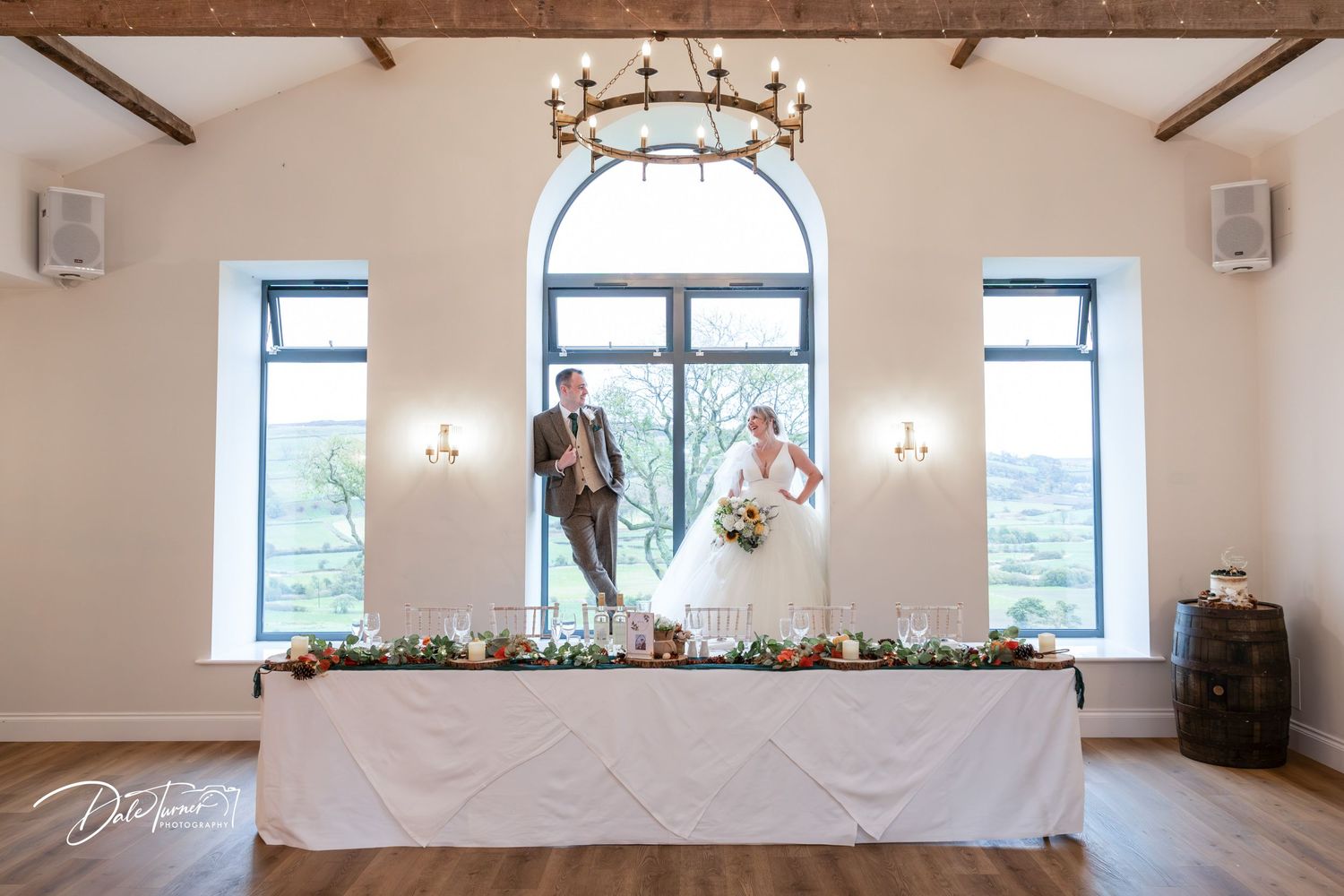 A bright, modern event venue with exposed wooden beams, white walls, and large windows letting in natural light.