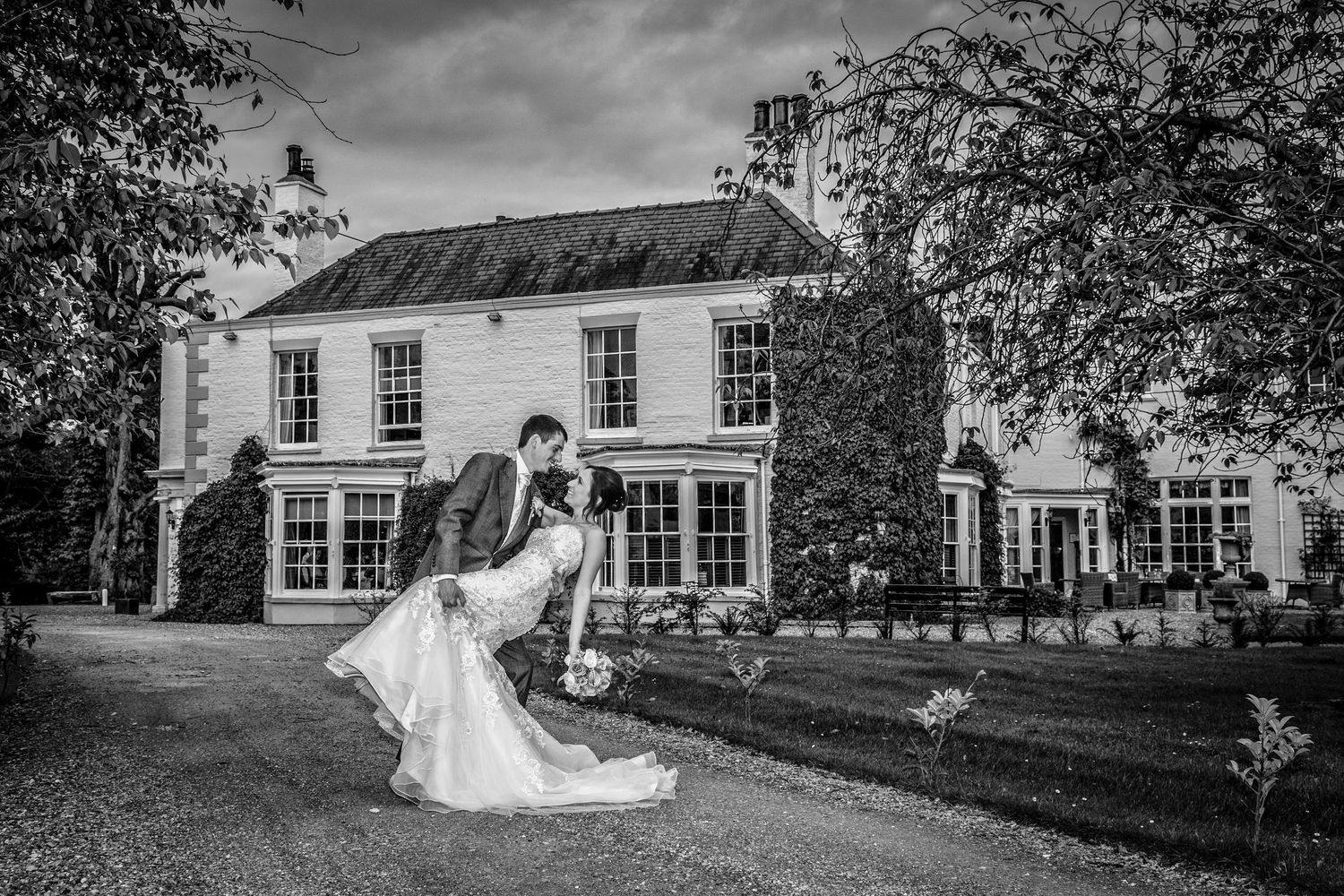 Black and white wedding portrait in front of classic country house.