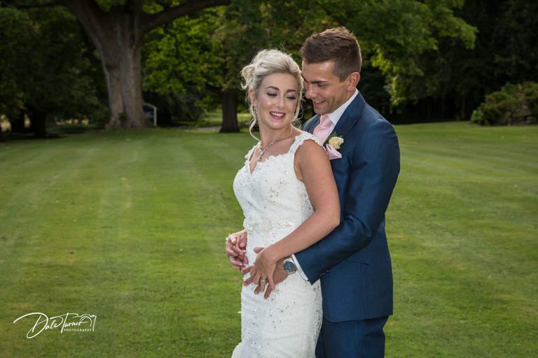 Joyful moment captured on expansive green lawn during summer wedding.