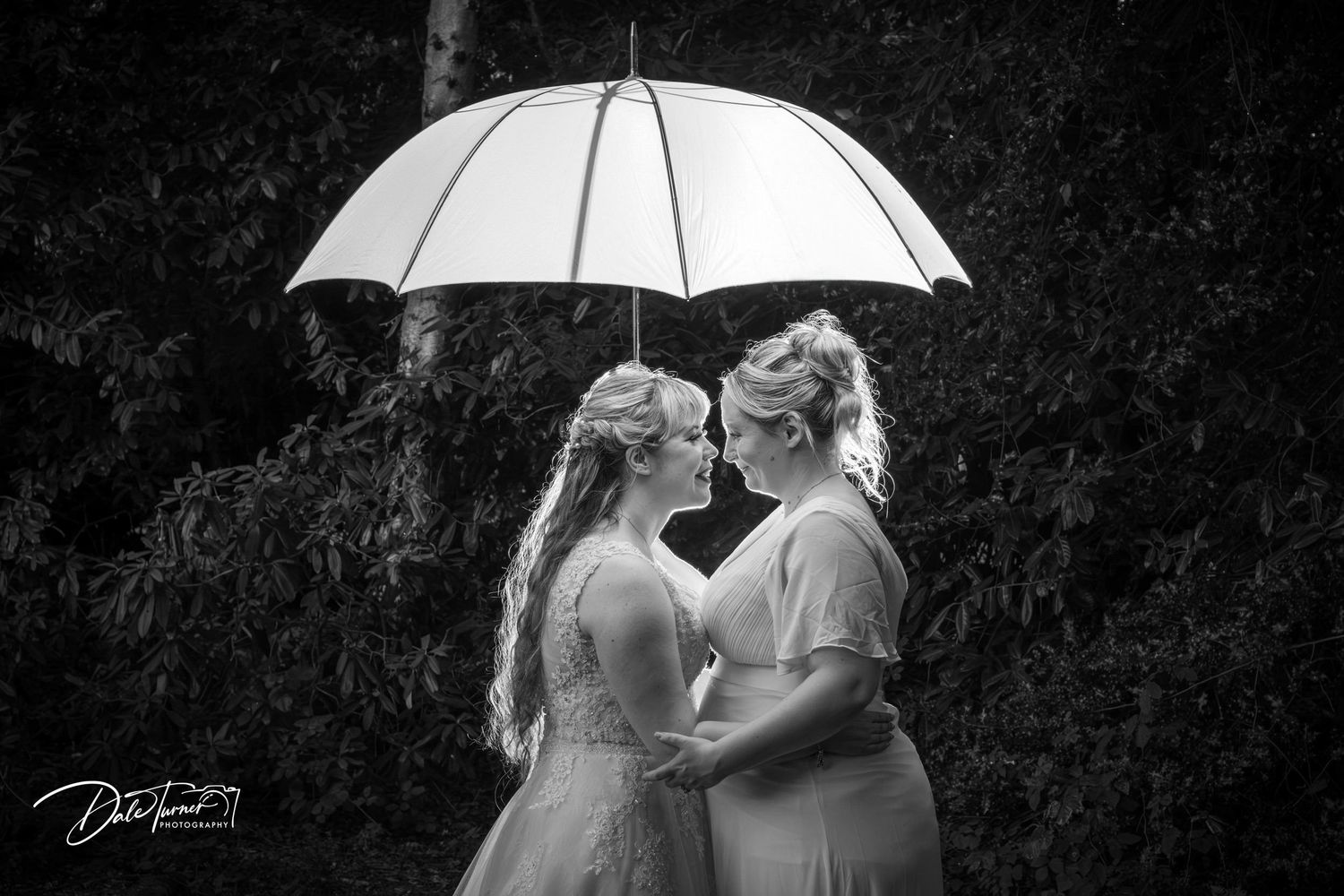 Artistic black and white wedding photos featuring a white umbrella and romantic poses.