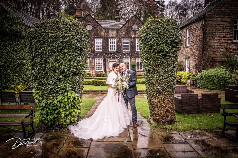 Wedding portrait in garden courtyard of historic ivy-covered stone building.
