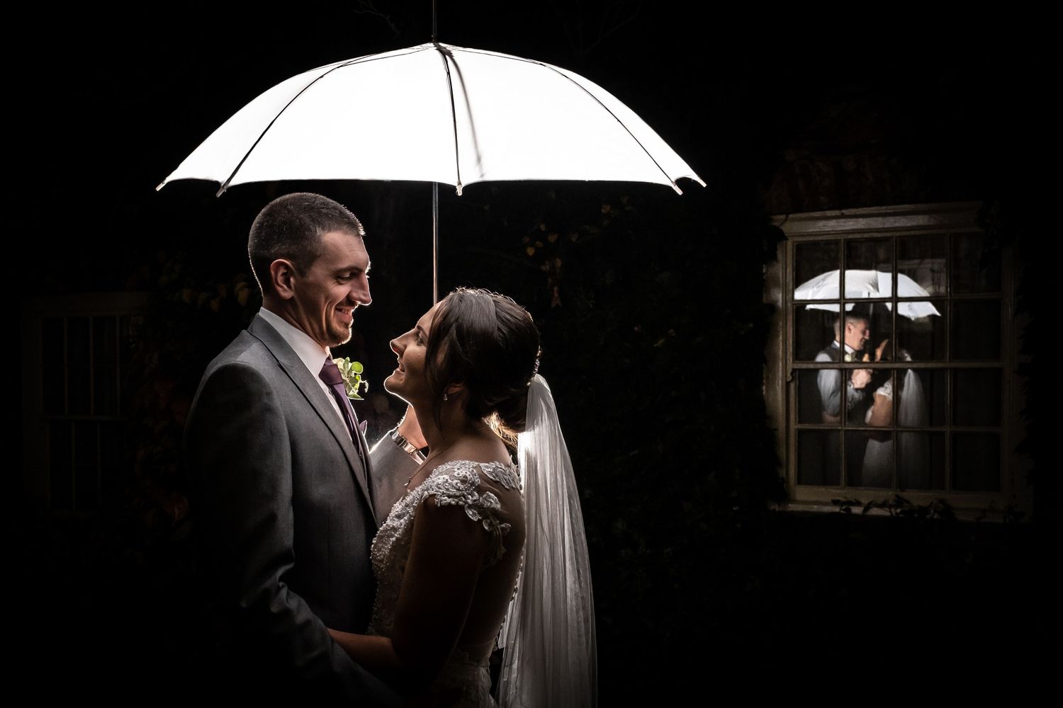 Dramatic low-light photography with white umbrella creating moody wedding portrait.