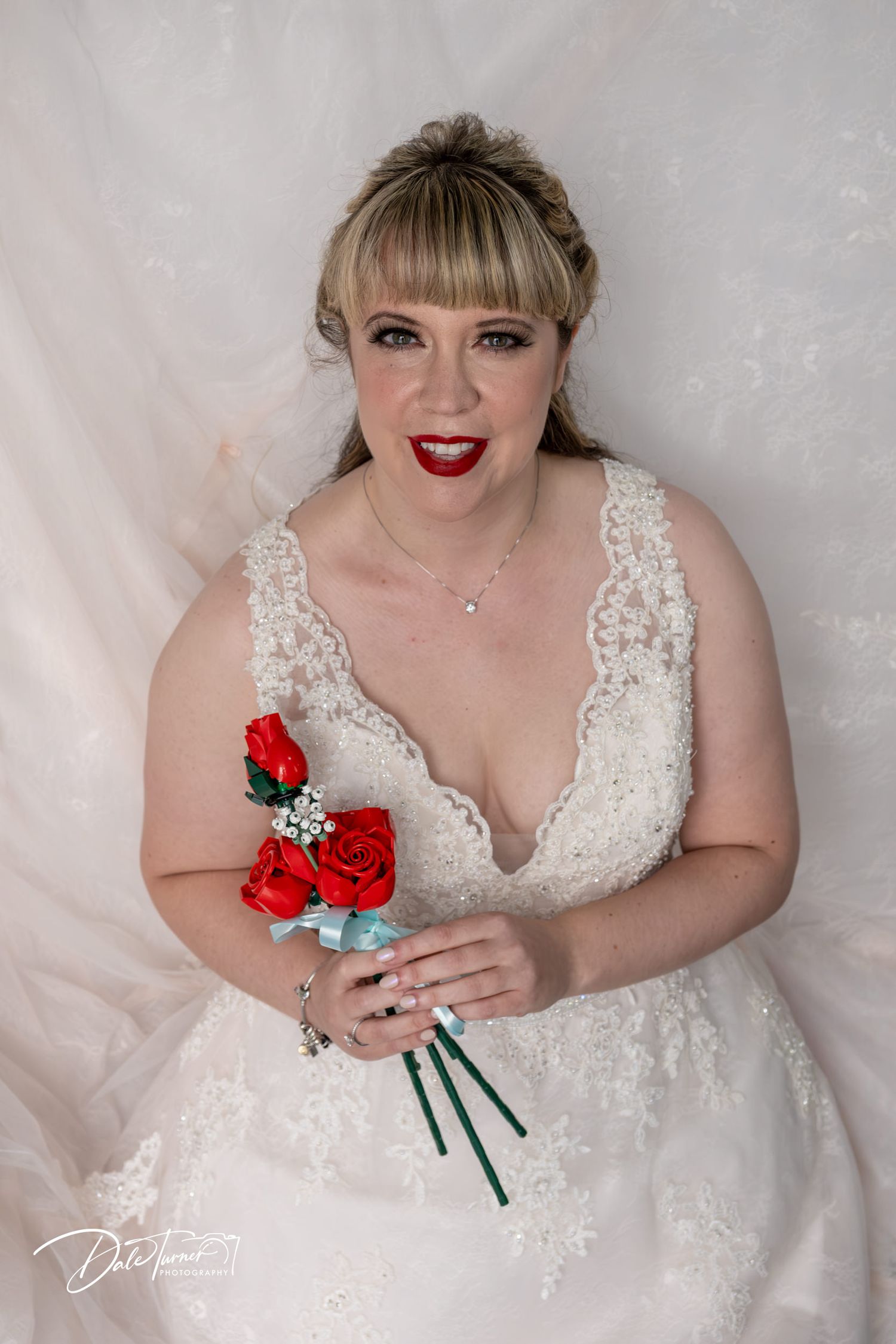 Wedding dress detail shots with red roses and delicate lace elements.