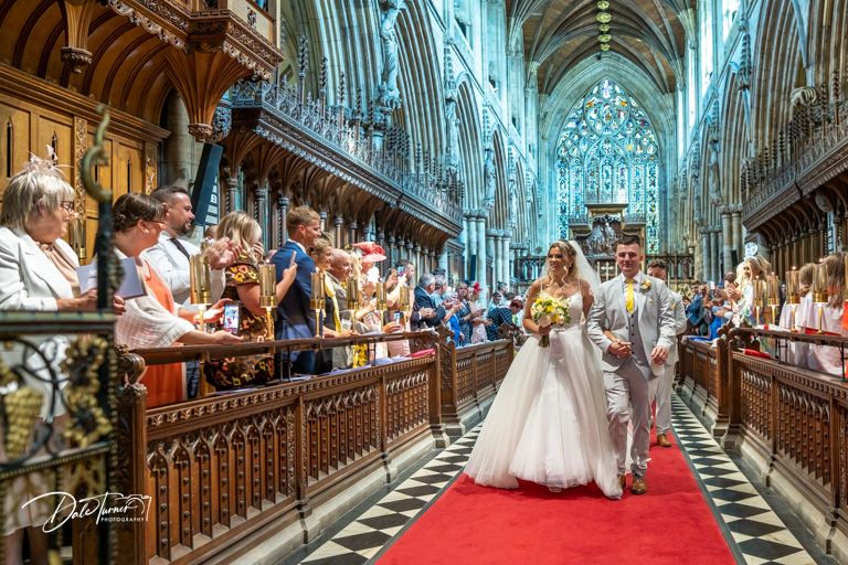 Stunning cathedral interior with vaulted ceilings and red carpet aisle during a wedding ceremony.