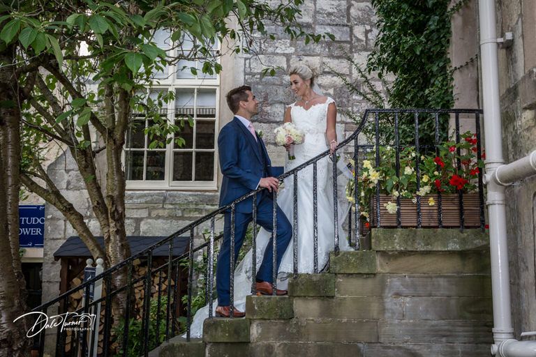 Stone building entrance with elegant archways and stairs creates romantic wedding backdrop.