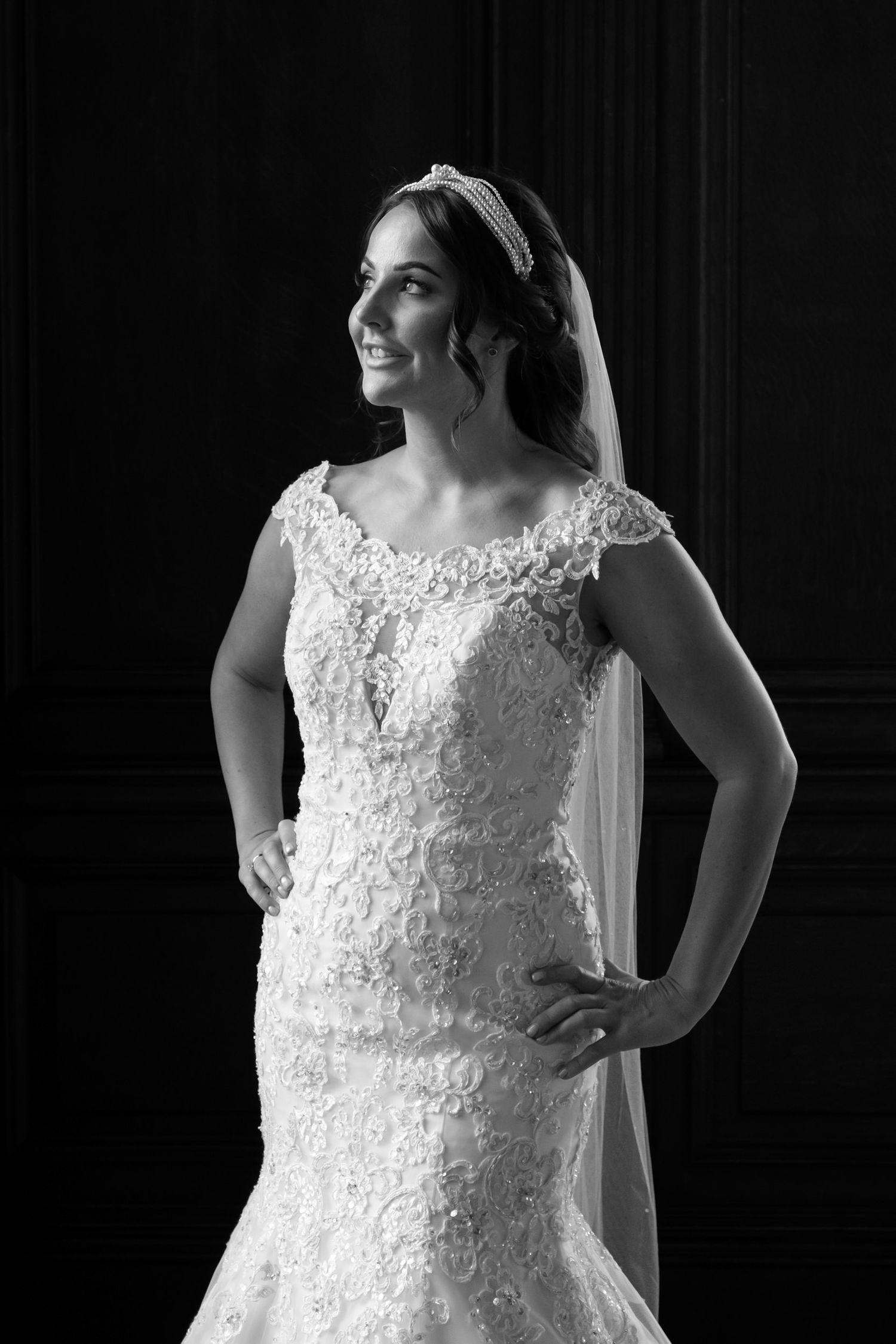 Elegant white lace wedding dress details shown in dramatic black and white photography.