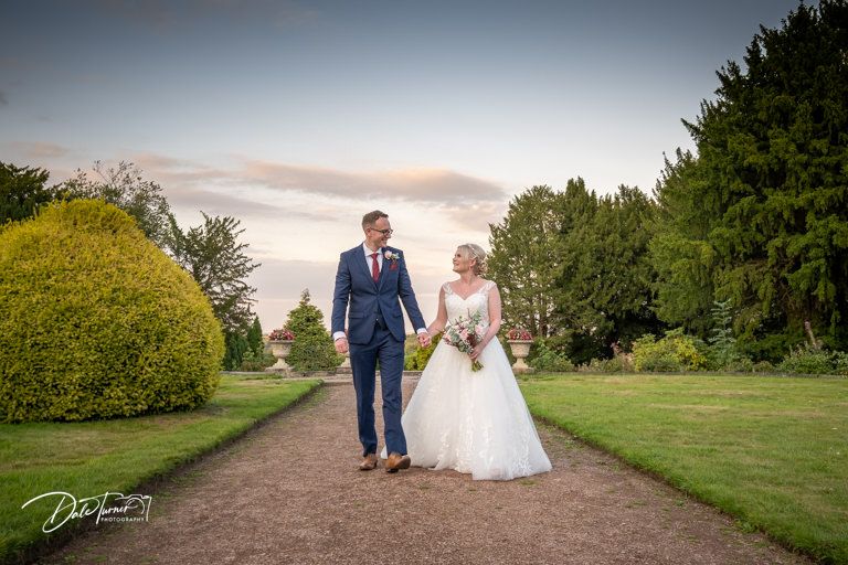 Wedding portraits captured along a scenic garden path during golden hour.