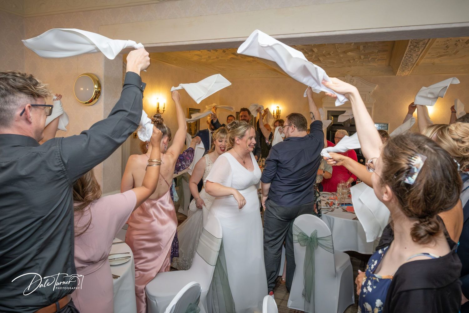 Wedding celebration with guests waving white napkins during a reception party.
