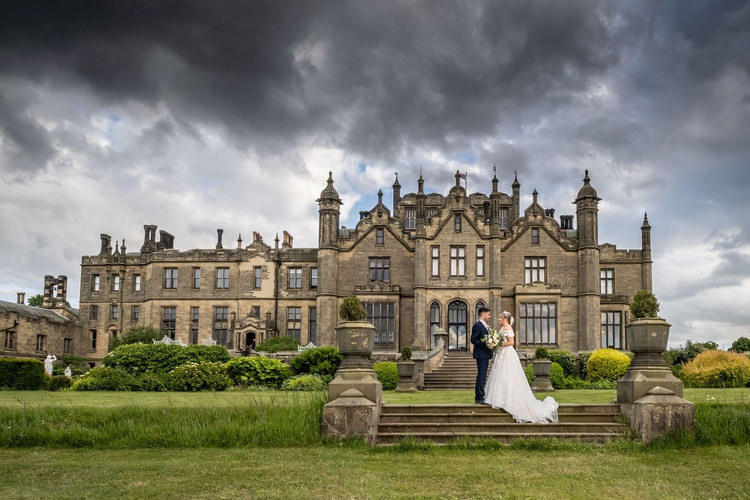 Panoramic view of a Gothic castle wedding venue under dramatic stormy skies.