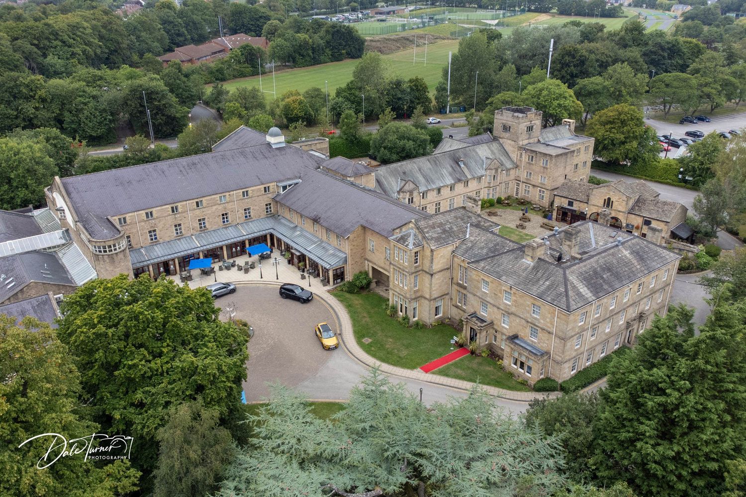 Aerial view of stone buildings and green grounds of an estate property.