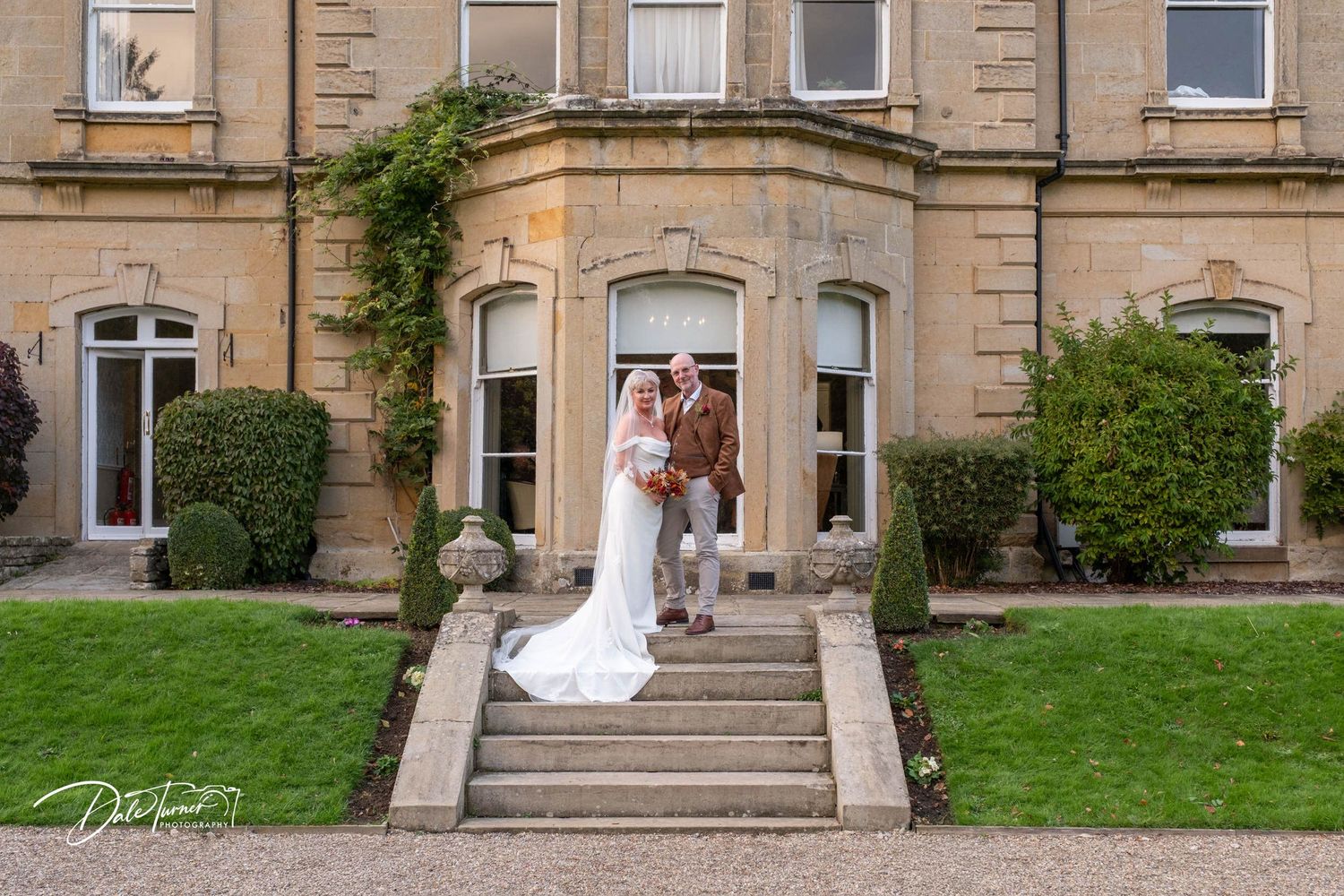 Historic stone building with grand entrance steps and landscaped grounds.