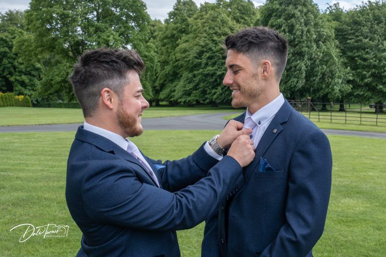 Groomsmen sharing lighthearted moments on the lawn of an elegant venue.
