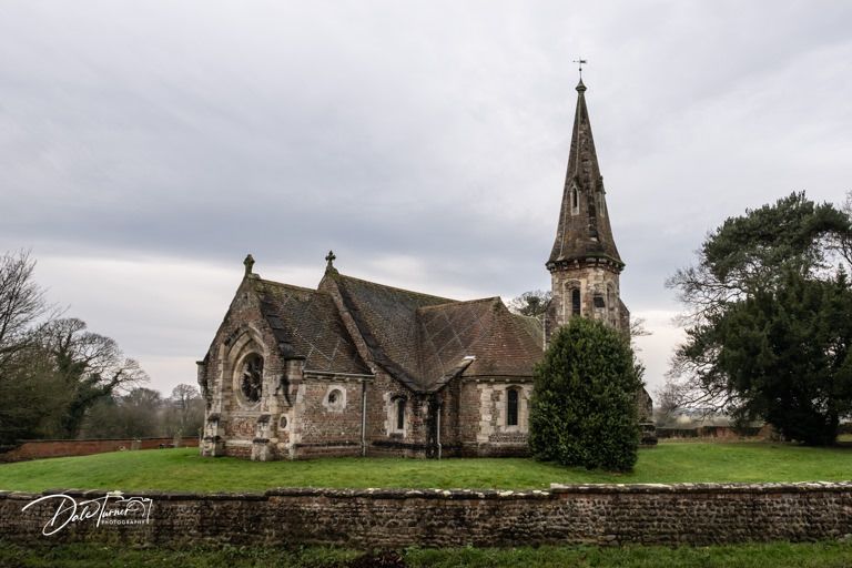 A historic stone church with Gothic spire stands against a moody cloudy sky.