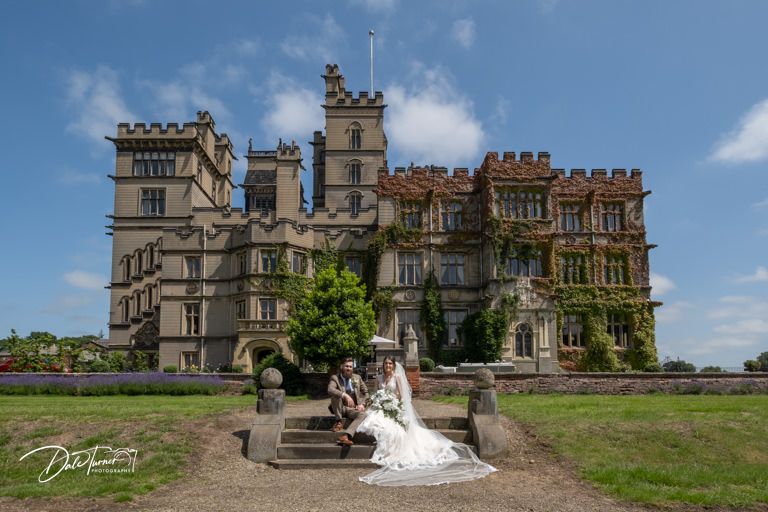 Panoramic view of a grand castle-like venue with stone architecture under blue sky.