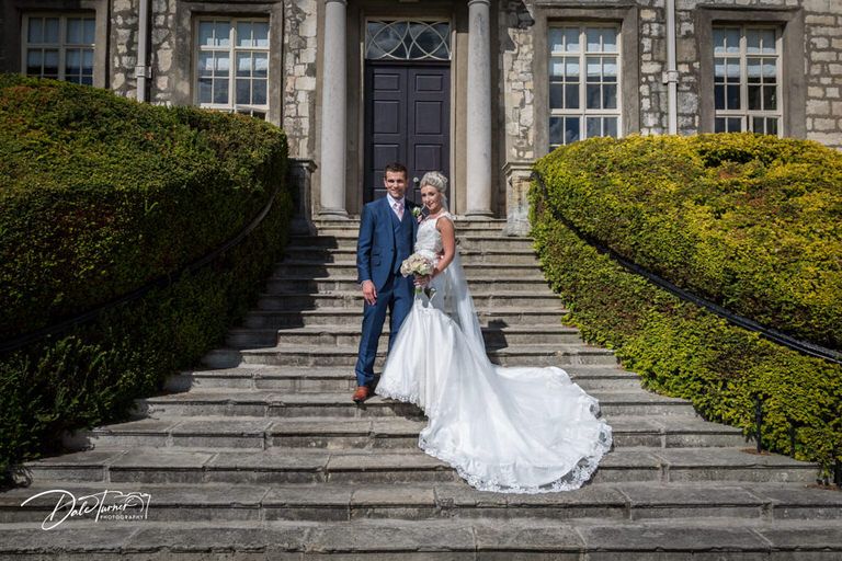 Elegant wedding portraits on stone steps of historic building.