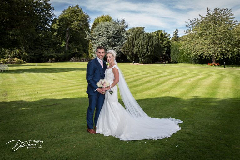 Scenic wedding photos on manicured green lawn with elegant landscaping.