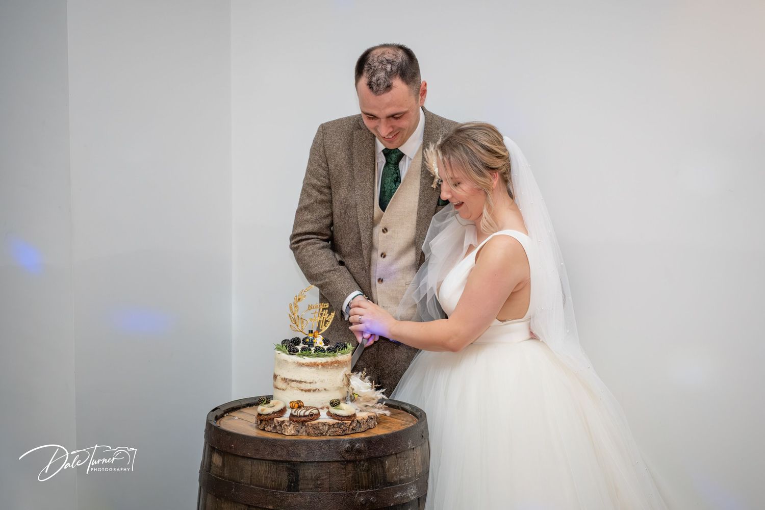 A bride and groom cut their rustic wedding cake together during their reception celebration.