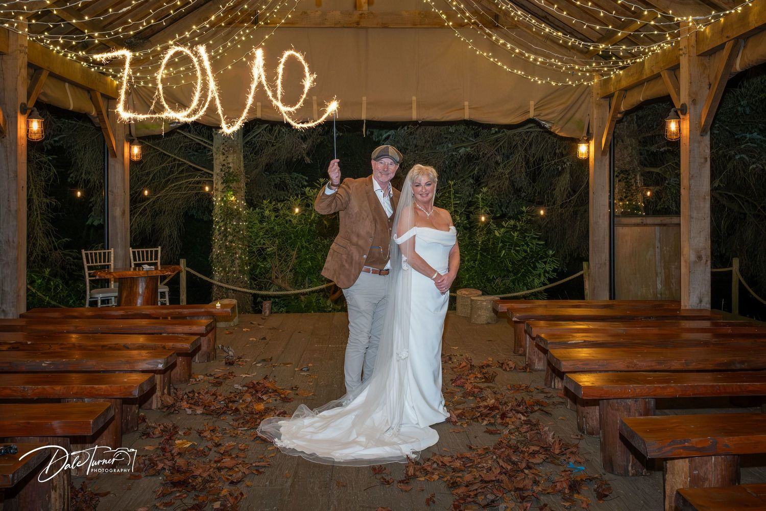 Rustic wedding venue with glowing string lights and illuminated LOVE sign on display.