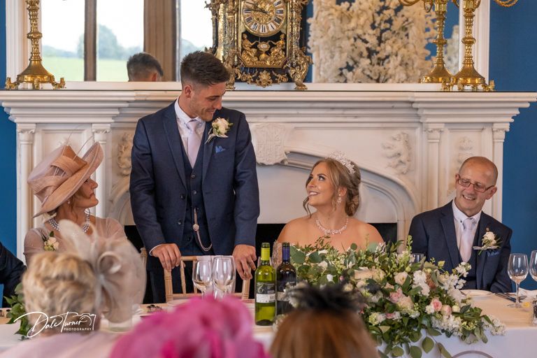Wedding reception dinner setup with floral centerpieces and elegant table settings.