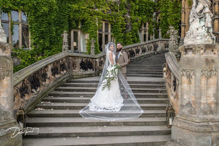 Wedding photograph on ivy-covered stone staircase of historic building.