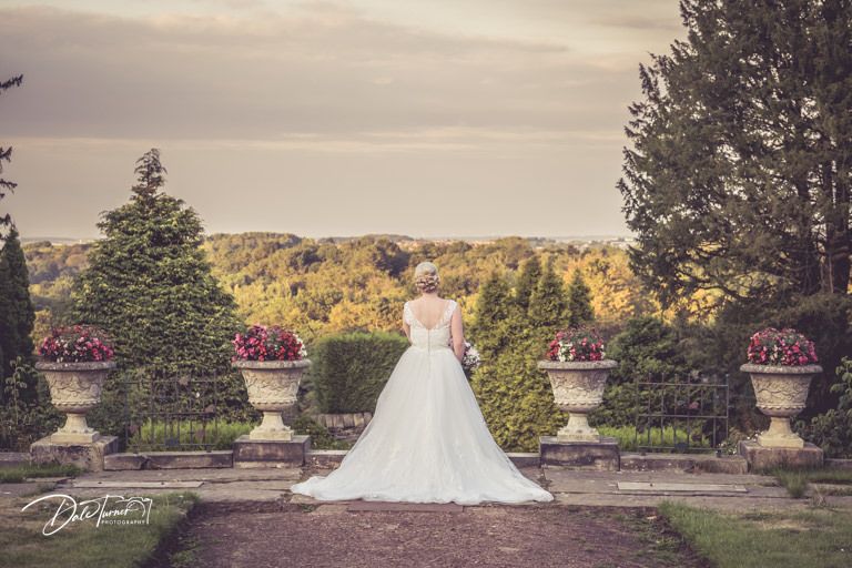 Wedding portraits in formal garden with decorative urns and flower arrangements.
