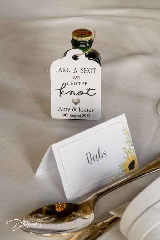 Wedding reception detail shots showing place cards and 'Take a Shot' favor tags.