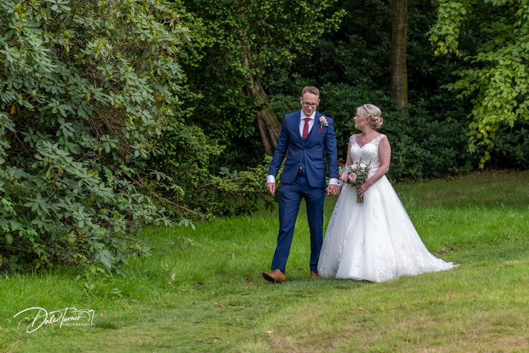 Wedding couple poses for photos in a lush green garden setting.