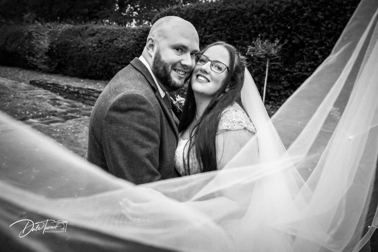 Romantic wedding portraits with flowing veil against natural outdoor backdrop.