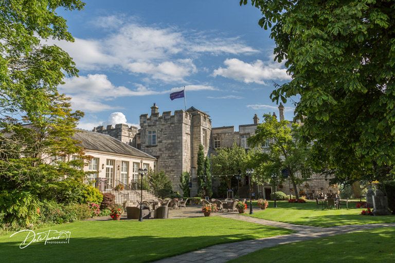 Scenic view of historic stone castle buildings and grounds with green lawn.