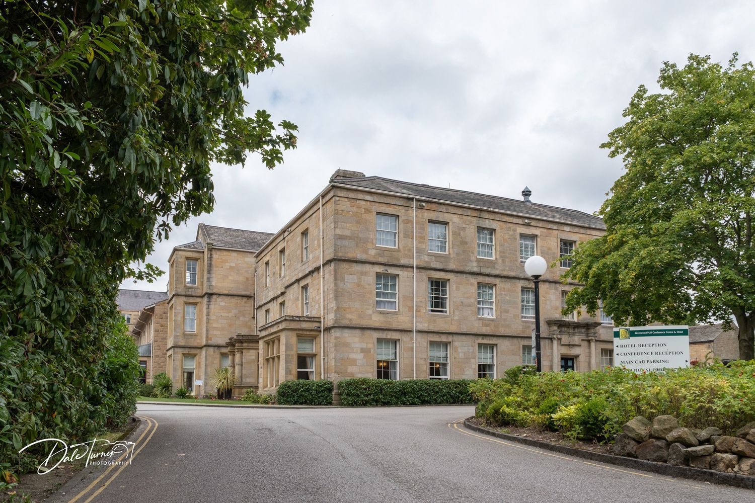 Exterior view of a historic stone building with multiple connected units and landscaping.