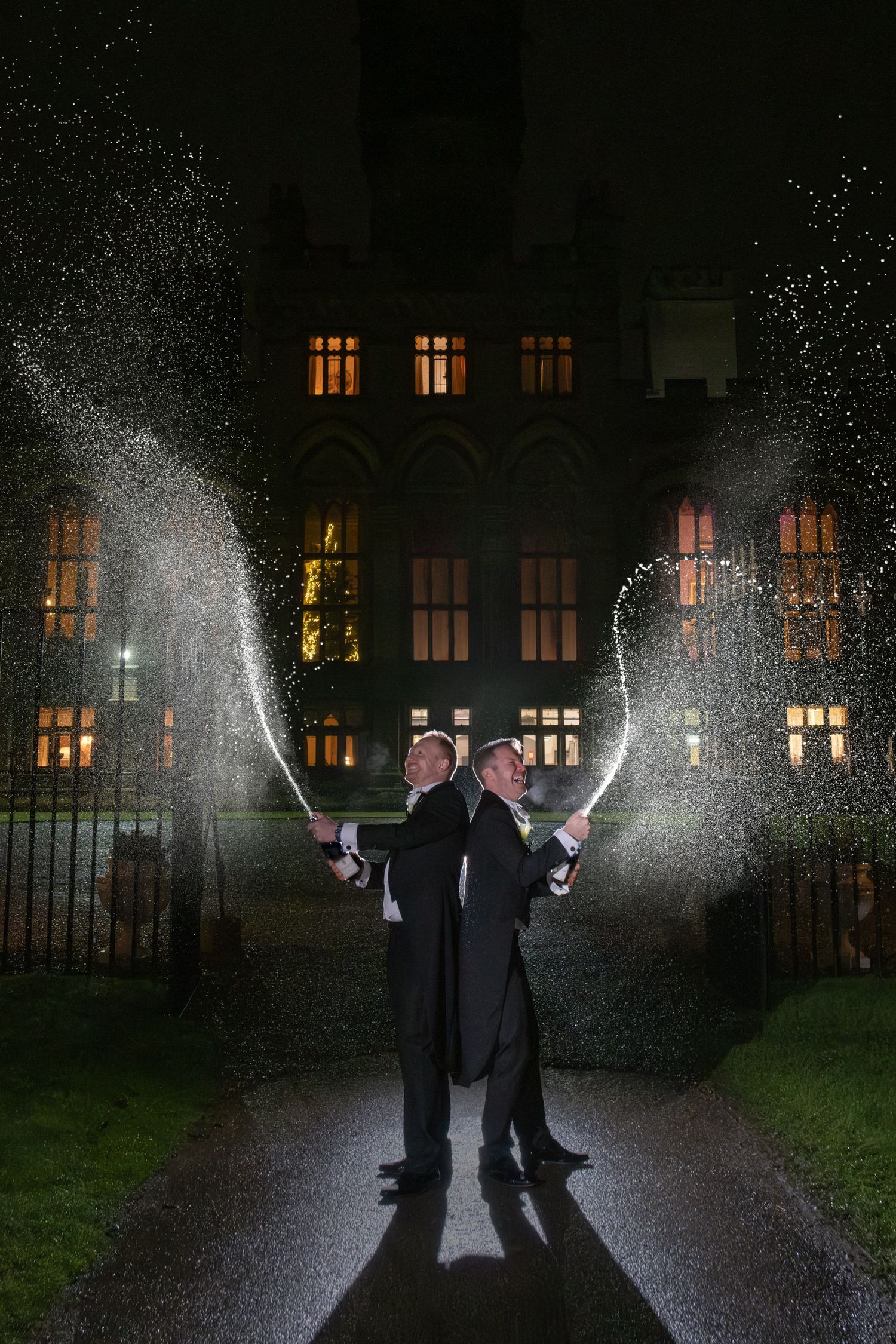 Nighttime sparkler photo with silhouettes against illuminated building windows.