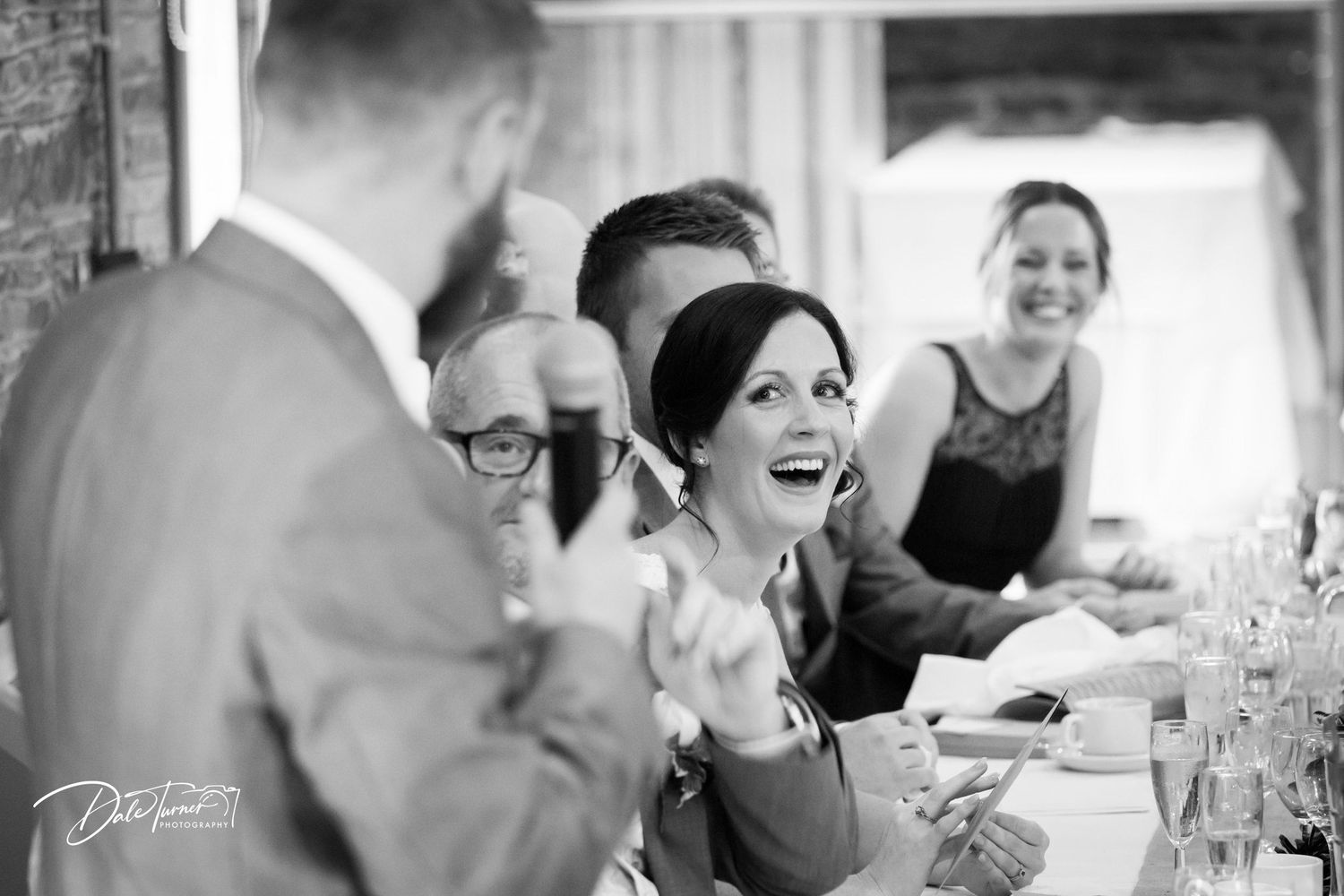 Wedding reception guests enjoying dinner and conversation in elegant banquet hall.