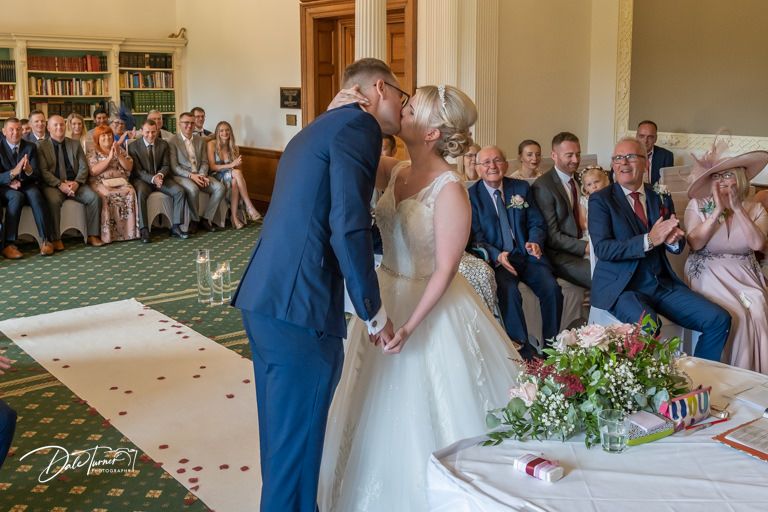 Wedding ceremony takes place in an elegant room with wooden details and bookshelves.