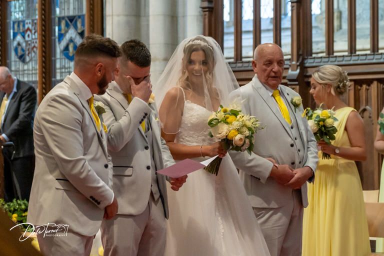 Wedding party in light colored attire gathered near cathedral's ornate altar area.
