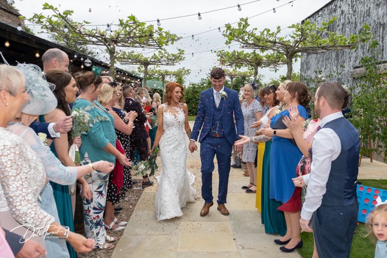 Wedding guests celebrate under string lights at an outdoor reception venue.