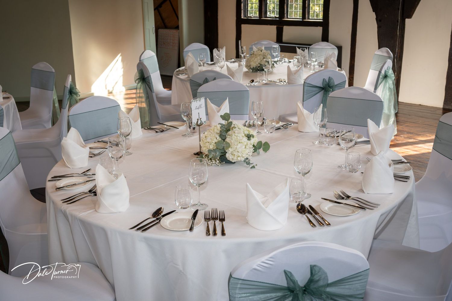 Elegant wedding reception tables set with white linens and mint green accents.