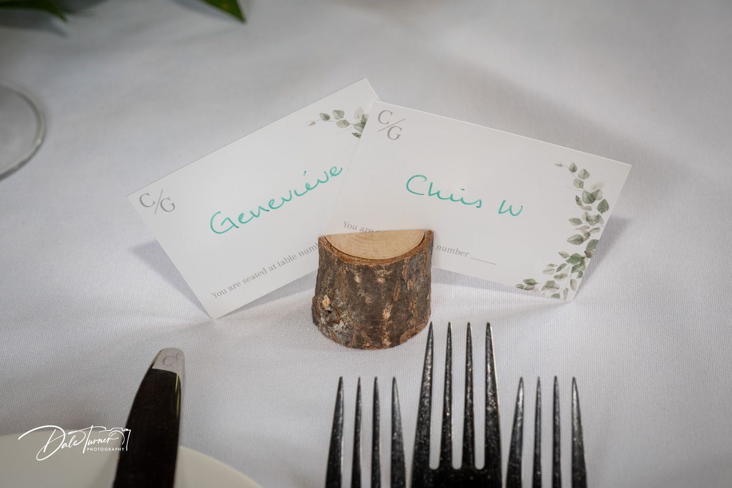 Wedding place cards displayed with rustic wood elements and delicate greenery.