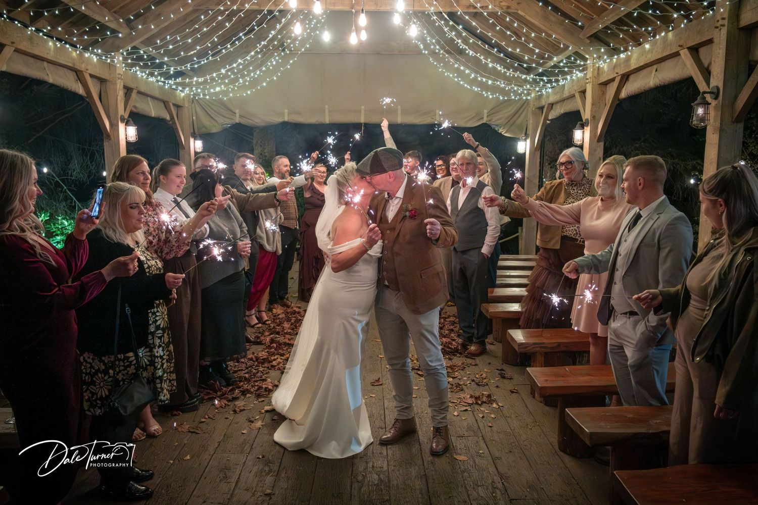 Wedding ceremony venue with string lights and wooden benches creating an intimate atmosphere.