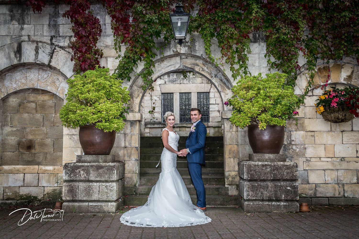 Stone archway entrance decorated with climbing vines creates romantic wedding setting.