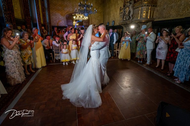 Wedding reception dance floor scene with guests watching the couple's first dance.