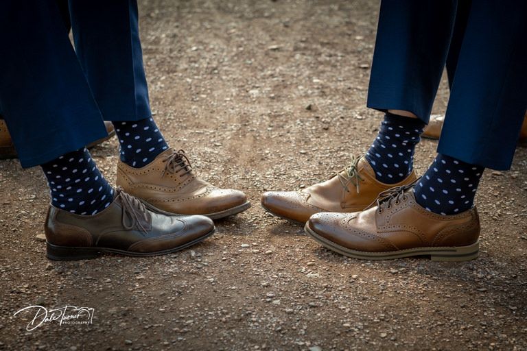 Close-up shot of polka dot socks and brown leather dress shoes on a dirt path.