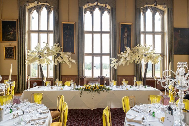 Formal dining hall with tall windows and elegant table settings for wedding reception.