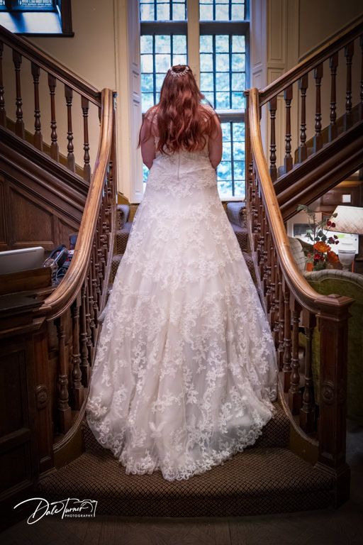 Detailed shots of ornate lace wedding dress on wooden staircase with natural window light.