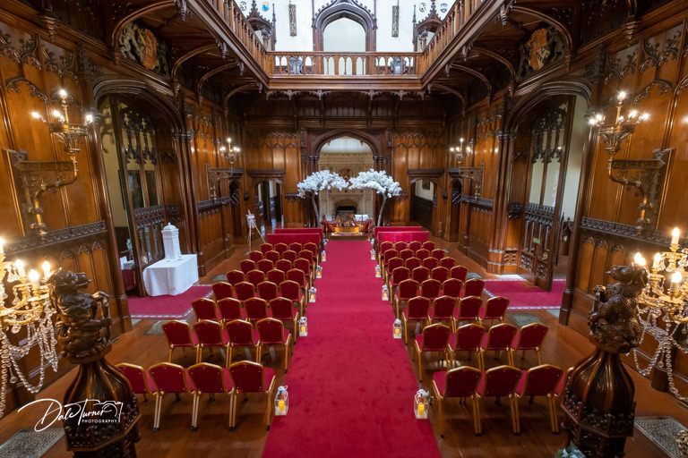Grand ceremonial hall with red velvet chairs and ornate wooden details.