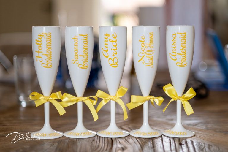 Row of champagne flutes decorated with yellow ribbons for a wedding celebration.