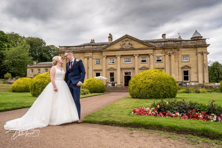 Elegant stone mansion with manicured gardens serves as backdrop for wedding photos.