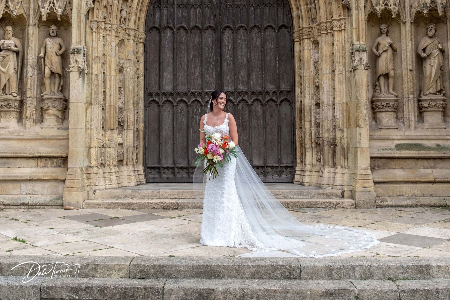 Wedding photography session against ornate Gothic cathedral doorway with detailed stonework.