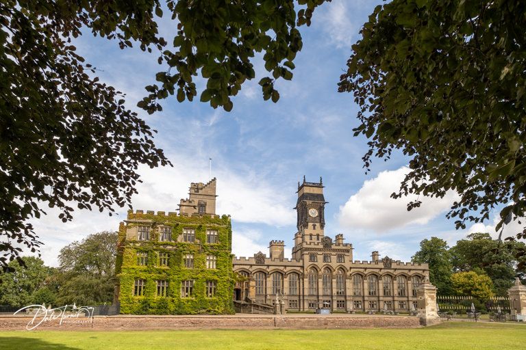 Panoramic view of a grand historic manor house with manicured grounds and classic architecture.