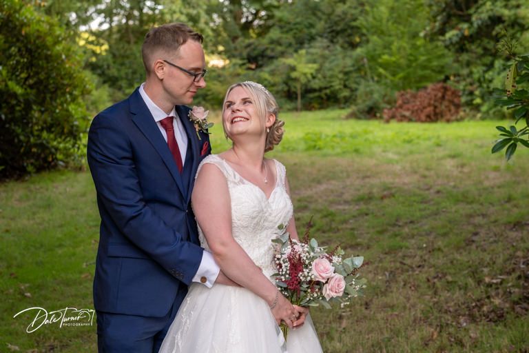 Candid wedding portrait captured in a natural garden setting.