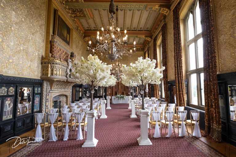 Elegant wedding reception hall with chandeliers and ornate decor set for celebration.